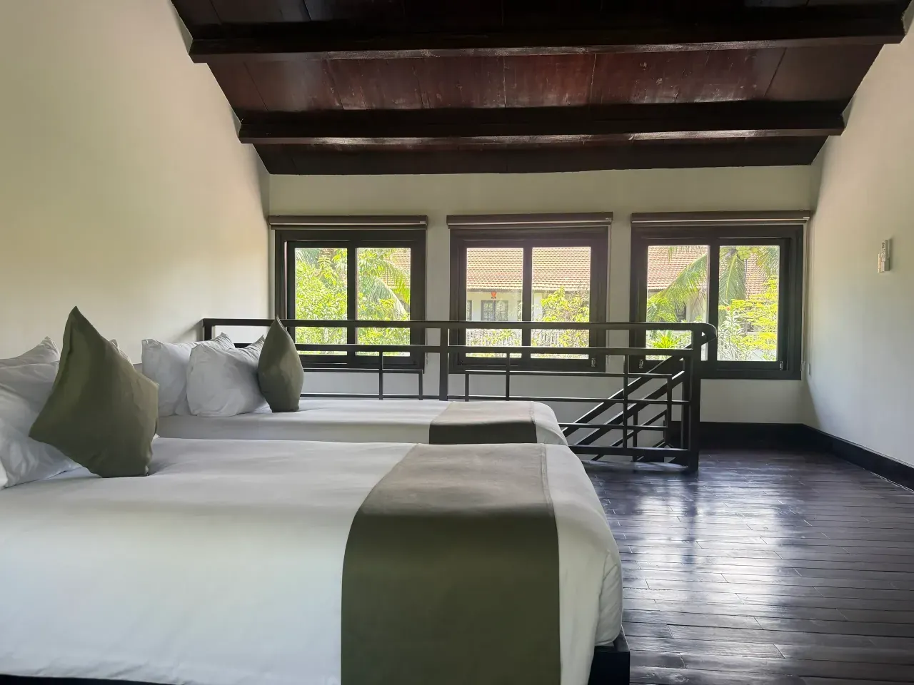 The upstairs bedroom of the Duplex Villa: two single beds under a beamed roof, with windows onto the garden