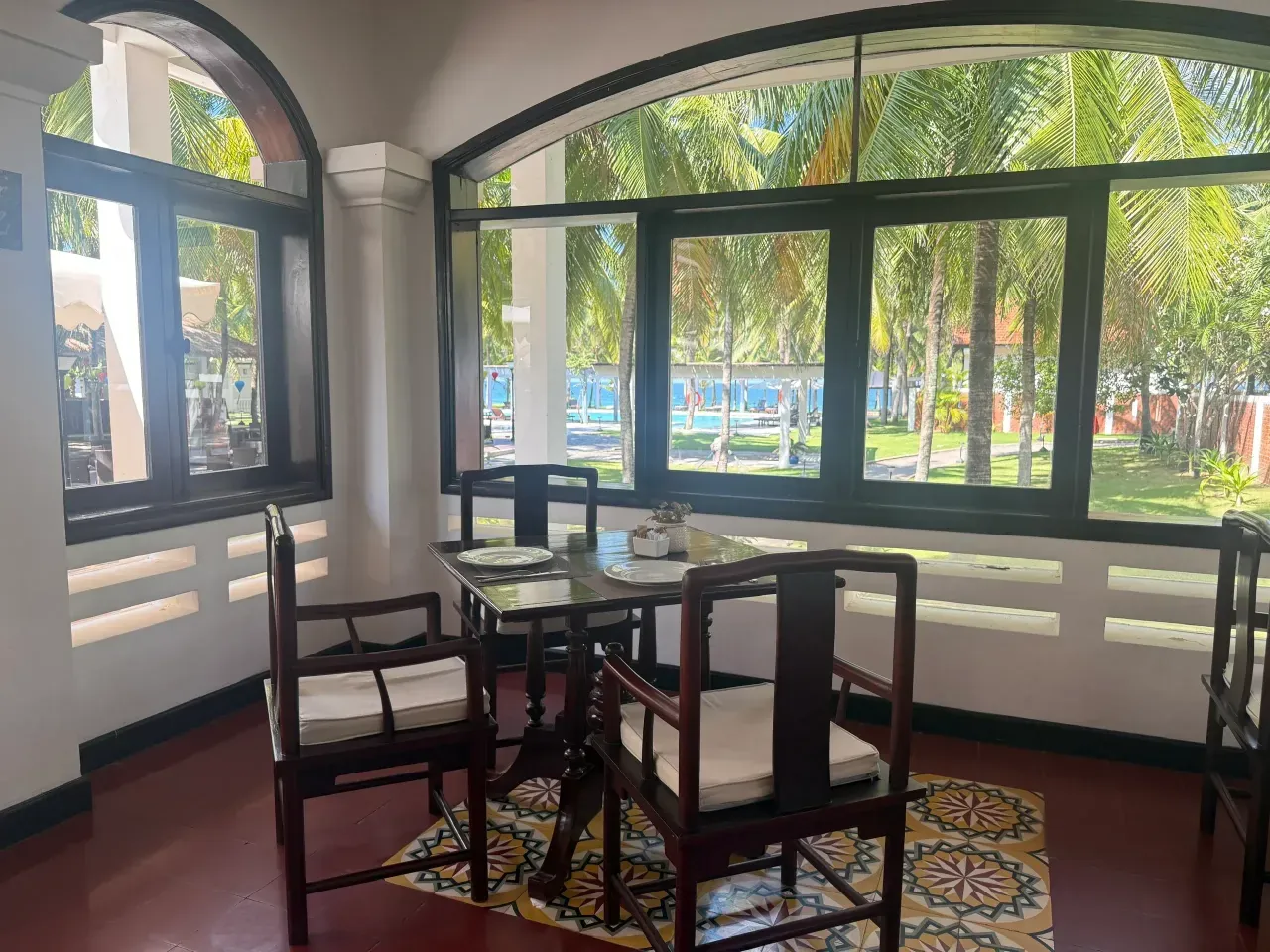 Inside Faifo: a table for two on patterned tiles, with arched windows onto the pool, the grove and the sea