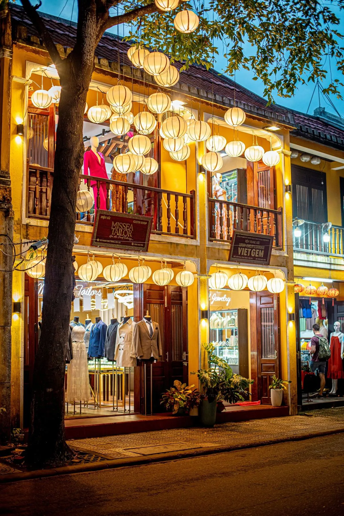 A tailor's shop in Hoi An at dusk, its lanterns lit over the street