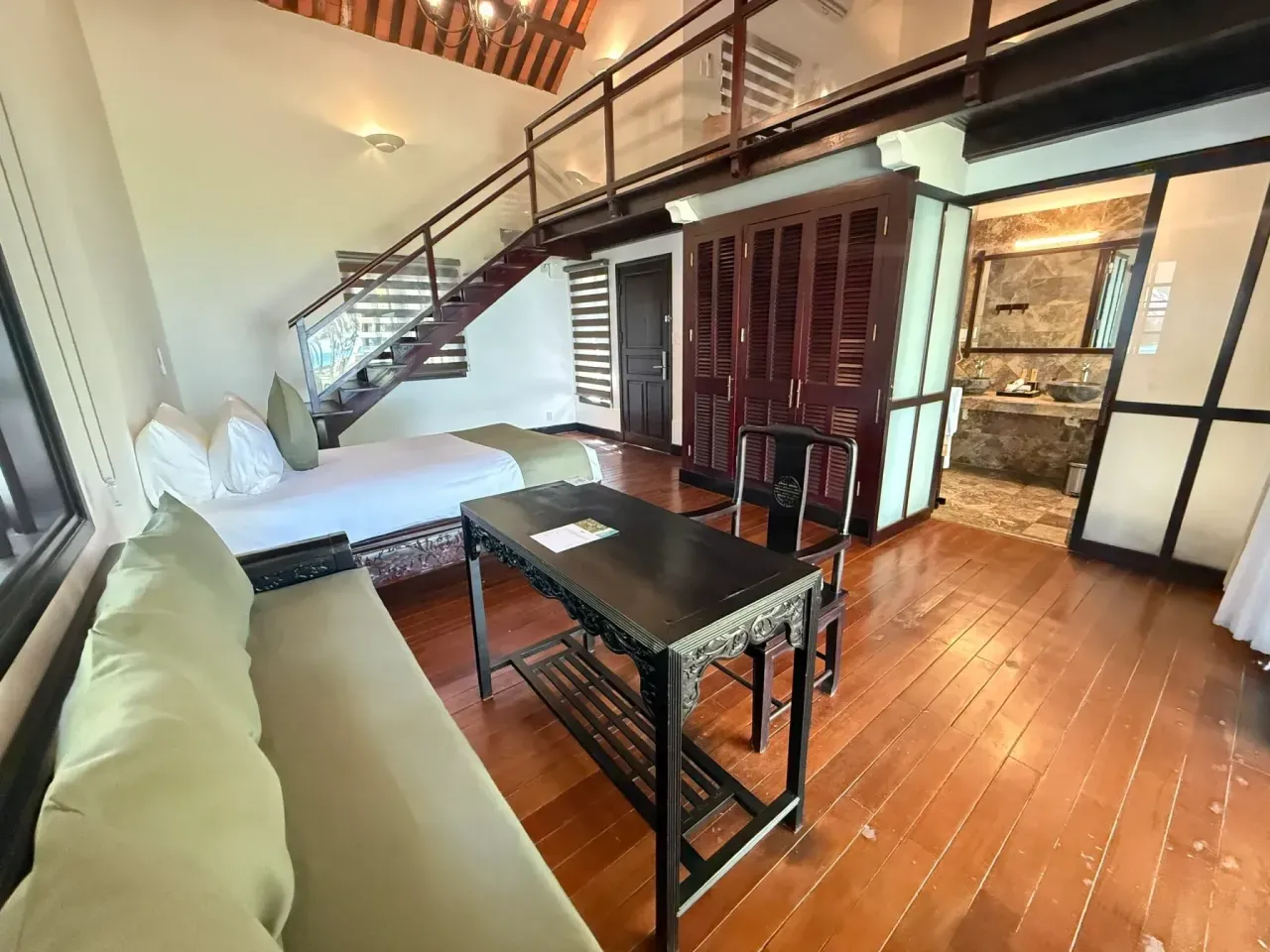 Planta baja de la Ocean Duplex Villa: sofá, escritorio, cama y la escalera al altillo