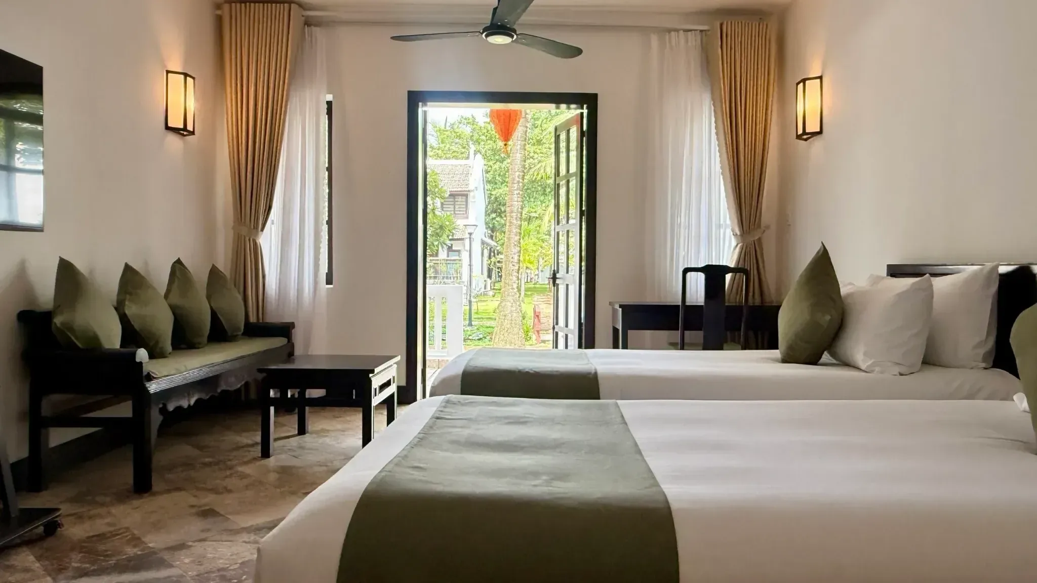 Standard Room con dos camas twin de camino verde oliva y la puerta de la terraza abierta al jardín
