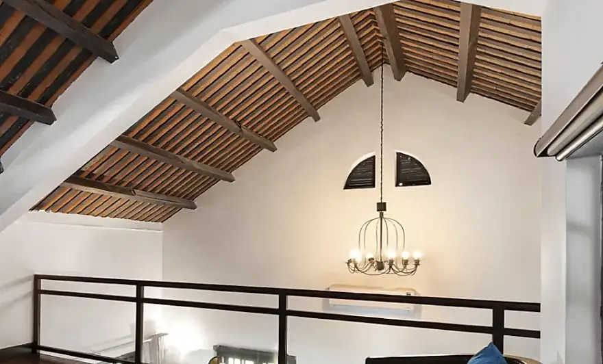 El altillo bajo el techo de vigas, con su lampara y la baranda