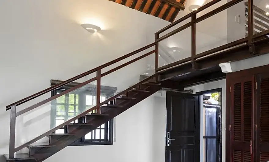 La escalera de madera al altillo, por delante de las puertas de celosia