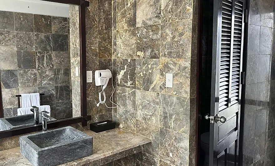 El bano de piedra, con su lavabo tallado y la puerta de celosia