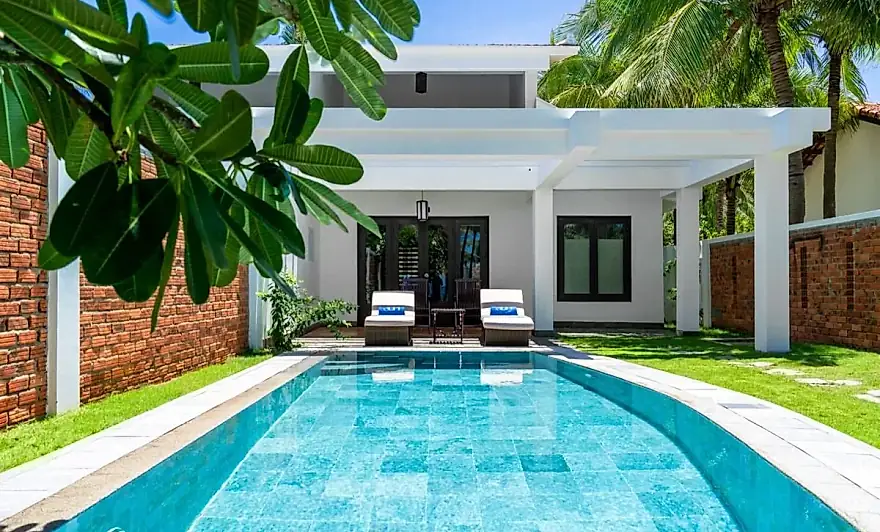 La villa vista a lo largo de su piscina privada, con muros de ladrillo y frangipani a los lados