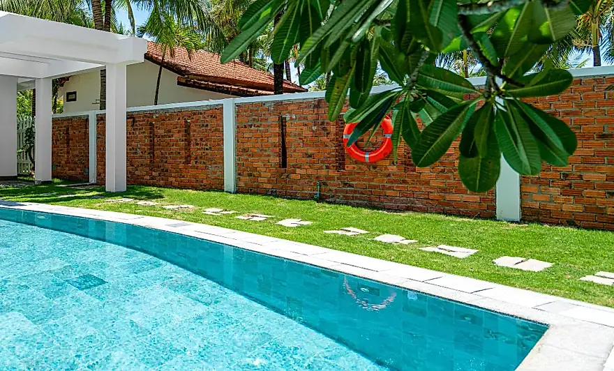 La piscina privada de lado a lado del jardin, cerrada por el muro de ladrillo